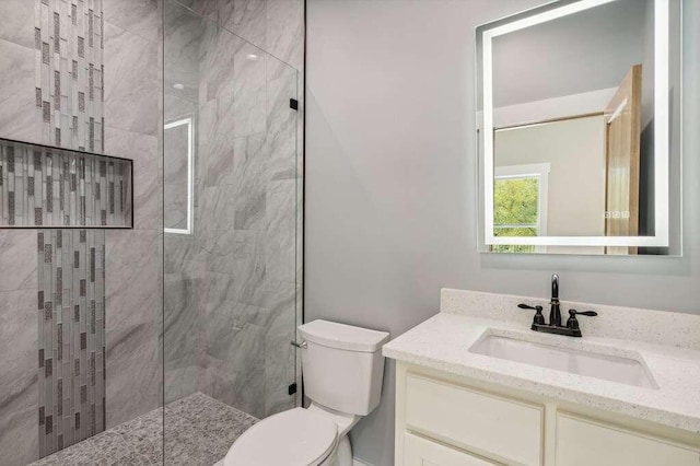 bathroom with tiled shower, vanity, and toilet