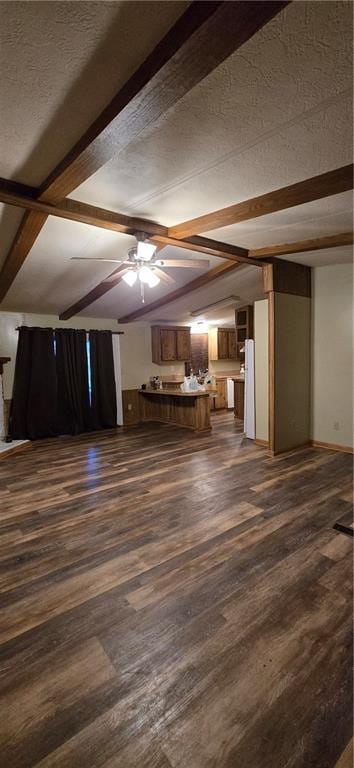 unfurnished living room with lofted ceiling with beams, ceiling fan, dark wood-type flooring, and a textured ceiling