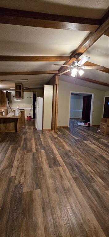 unfurnished living room with vaulted ceiling with beams, ceiling fan, and dark wood-type flooring