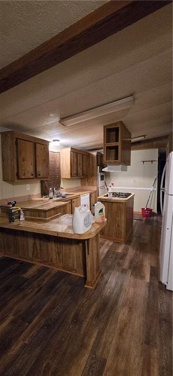 kitchen with sink, dark hardwood / wood-style flooring, beamed ceiling, kitchen peninsula, and white fridge