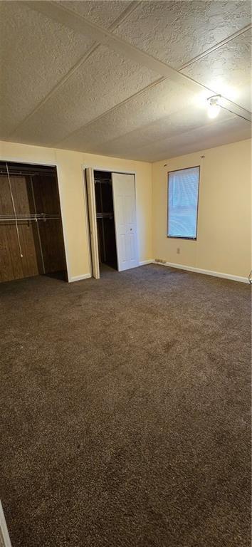 unfurnished bedroom with dark carpet