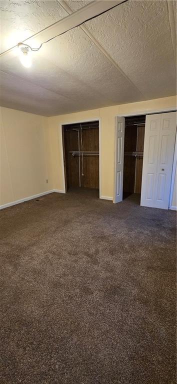 unfurnished bedroom featuring dark carpet and a textured ceiling