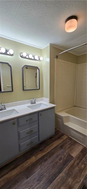 bathroom featuring  shower combination, a textured ceiling, hardwood / wood-style flooring, vanity, and ornamental molding