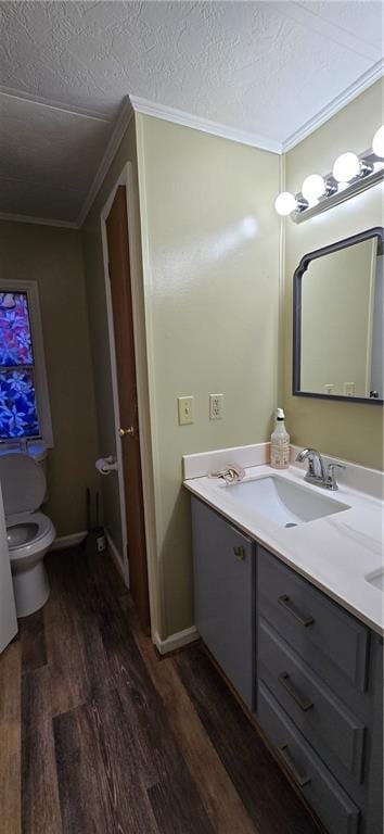 bathroom with ornamental molding, a textured ceiling, toilet, vanity, and hardwood / wood-style flooring