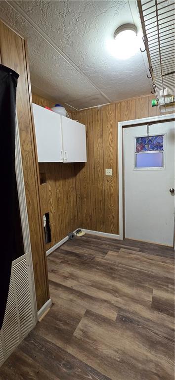 washroom with wooden walls, dark hardwood / wood-style flooring, and a textured ceiling