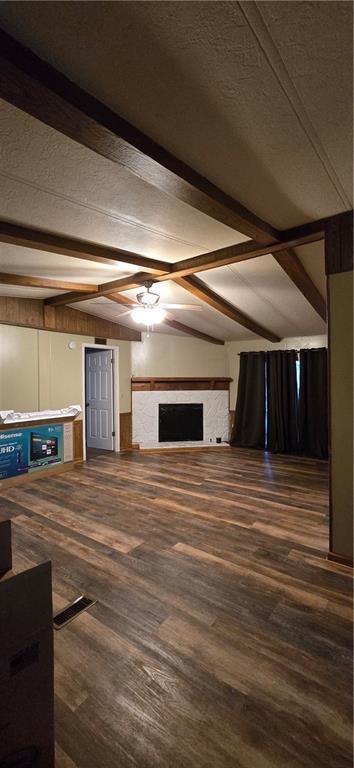 unfurnished living room with vaulted ceiling with beams and dark wood-type flooring