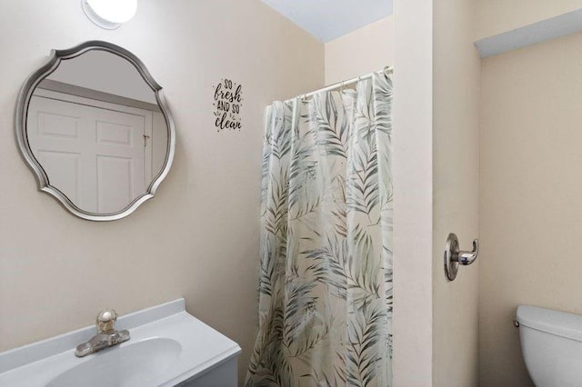 bathroom featuring a shower with shower curtain, vanity, and toilet