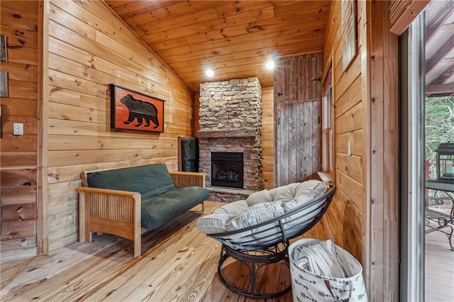 sitting room featuring wood walls, lofted ceiling, a fireplace, light hardwood / wood-style floors, and wood ceiling