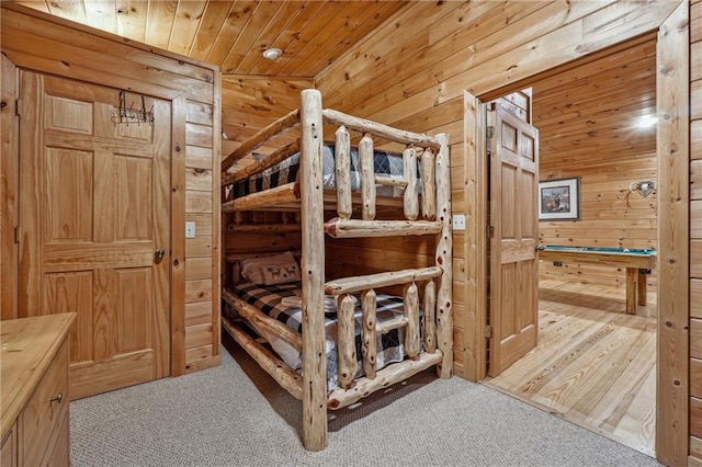 bedroom featuring wood walls, wooden ceiling, light carpet, and vaulted ceiling