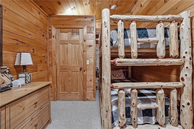 bedroom with wooden walls, light colored carpet, and wood ceiling