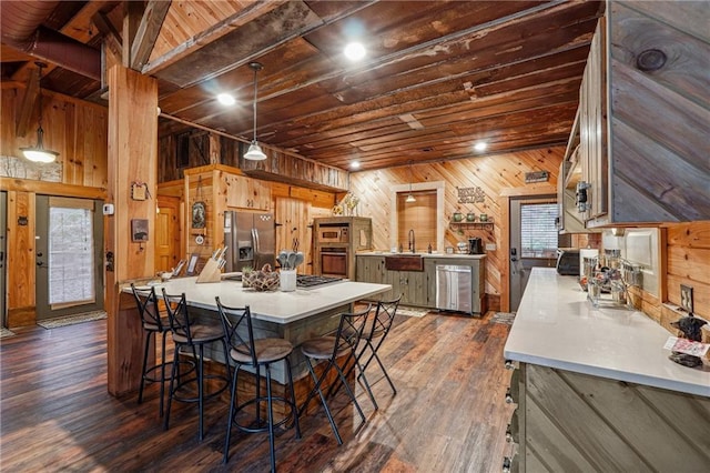 kitchen featuring stainless steel appliances, dark hardwood / wood-style flooring, a kitchen bar, wooden walls, and wood ceiling