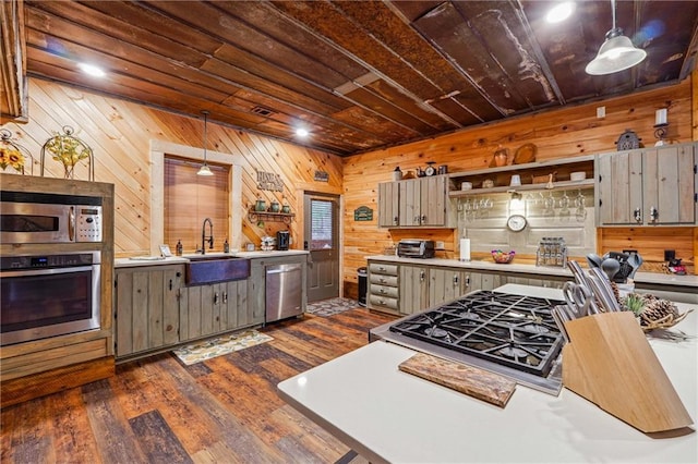 kitchen featuring wood walls, dark wood-type flooring, pendant lighting, and appliances with stainless steel finishes