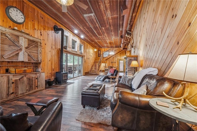 living room featuring ceiling fan, wooden walls, wooden ceiling, dark hardwood / wood-style floors, and a wood stove