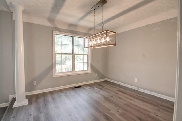 2773 Hawk Trace Ct NE, Marietta, GA 30066 - unfurnished dining area featuring ornate columns, dark wood-type flooring, a chandelier, and a textured ceiling