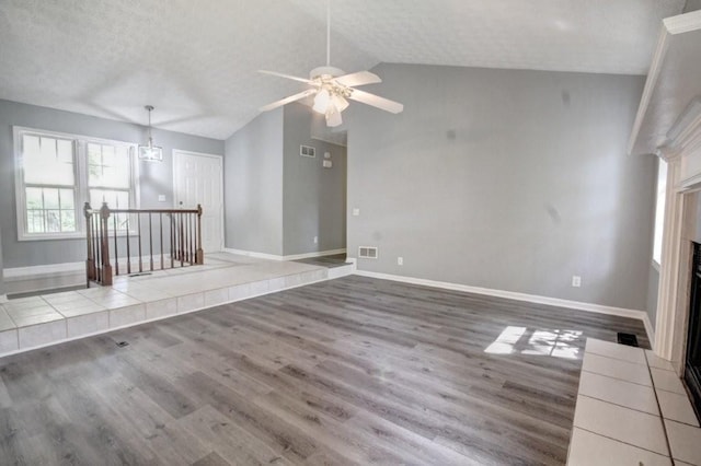2773 Hawk Trace Ct NE, Marietta, GA 30066 - unfurnished living room featuring a tile fireplace, wood finished floors, a ceiling fan, lofted ceiling, and a textured ceiling