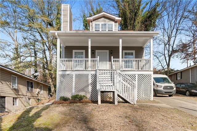 view of front of home with stairs, covered porch, and a chimney