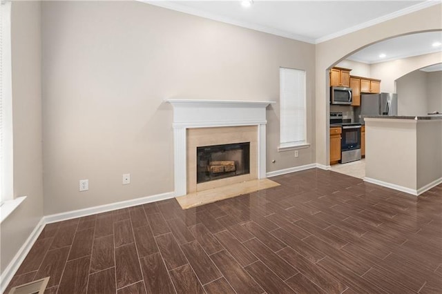 unfurnished living room with crown molding, baseboards, wood tiled floor, a fireplace, and arched walkways