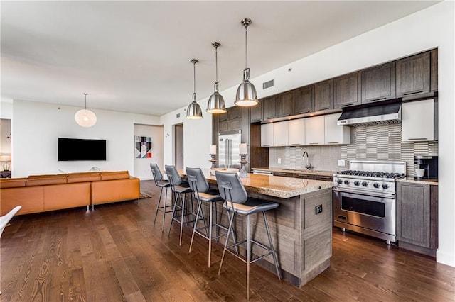 kitchen featuring a breakfast bar area, dark brown cabinets, a center island, dark wood-type flooring, and high quality appliances