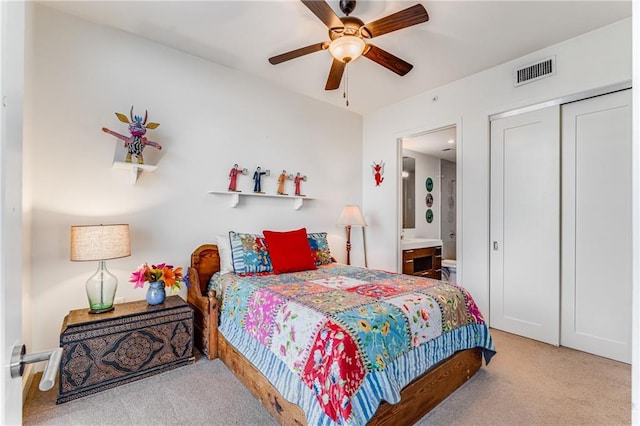 carpeted bedroom with a closet, ceiling fan, and ensuite bathroom