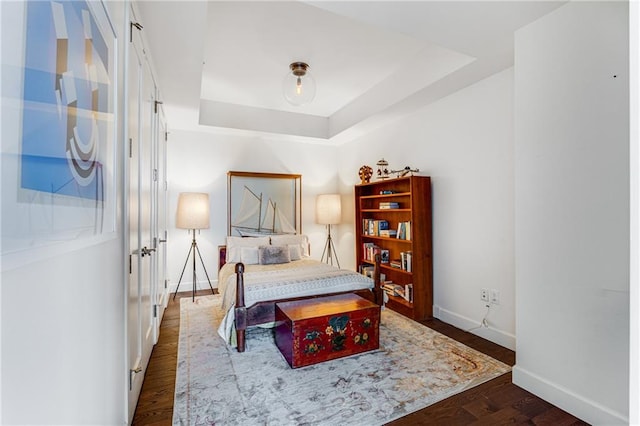 bedroom featuring dark hardwood / wood-style flooring and a tray ceiling