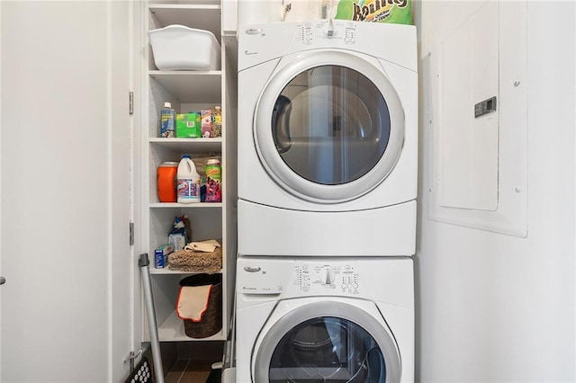 laundry area with stacked washer / drying machine and electric panel