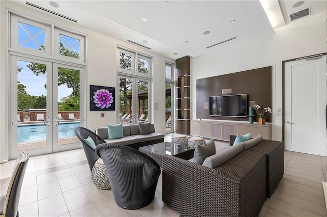 tiled living room with a wealth of natural light, french doors, and a towering ceiling