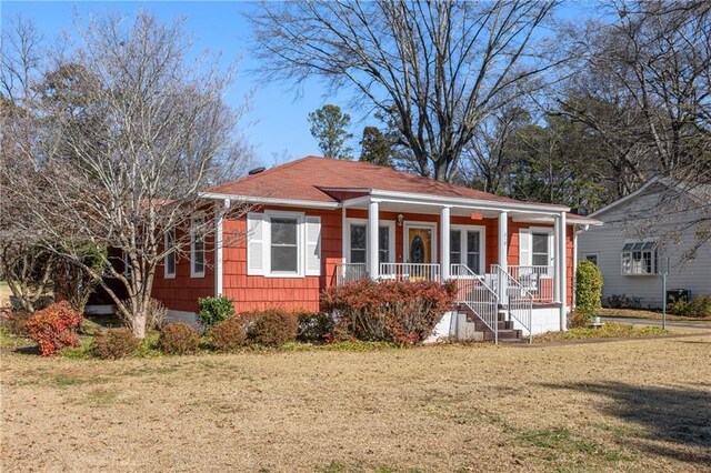 view of front of house featuring an outbuilding, a porch, a garage, and a front lawn