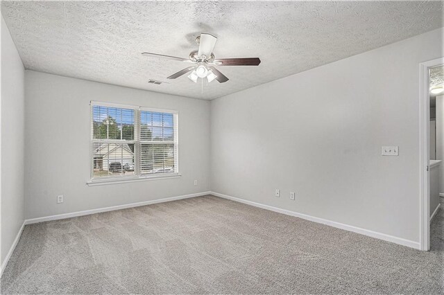 empty room featuring ceiling fan, a textured ceiling, and carpet