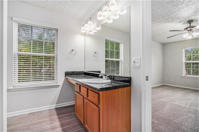 bathroom featuring wood-type flooring, vanity, a textured ceiling, and ceiling fan