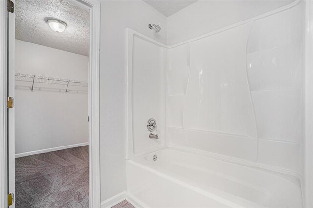 bathroom with a textured ceiling and tub / shower combination