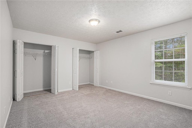 unfurnished bedroom with a textured ceiling and light colored carpet