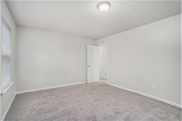 unfurnished room with a textured ceiling and carpet floors