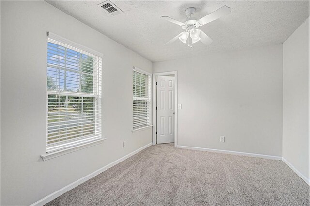 unfurnished room featuring ceiling fan, light colored carpet, and a textured ceiling