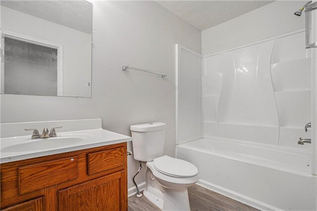 full bathroom featuring vanity, toilet, bathtub / shower combination, a textured ceiling, and hardwood / wood-style floors