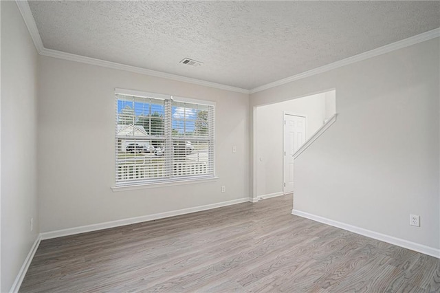 empty room featuring ornamental molding, light hardwood / wood-style floors, and a textured ceiling