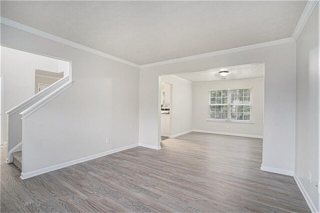 unfurnished living room featuring ornamental molding, a textured ceiling, and hardwood / wood-style flooring