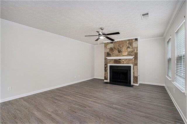 unfurnished living room with a wealth of natural light, ceiling fan, dark wood-type flooring, and a stone fireplace