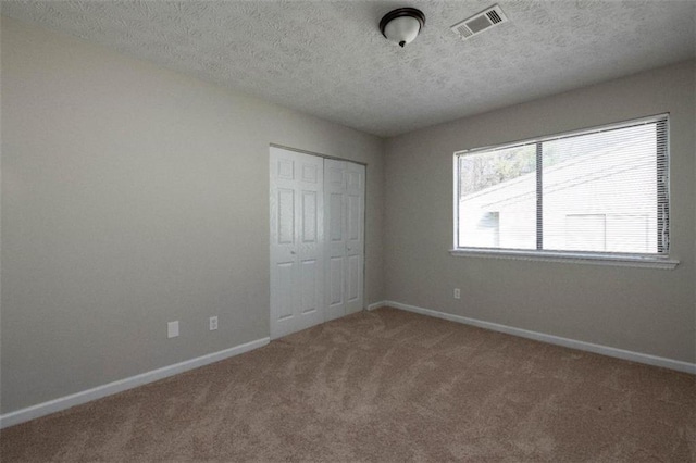 unfurnished bedroom featuring carpet floors, baseboards, visible vents, and a closet