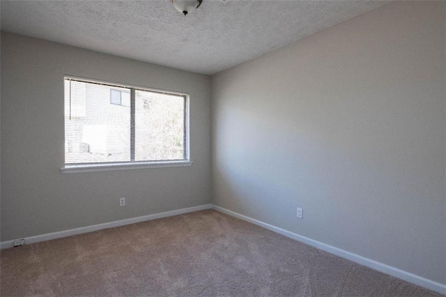 carpeted spare room featuring a textured ceiling and baseboards