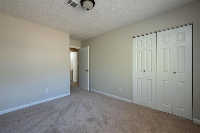 unfurnished bedroom with baseboards, visible vents, carpet, a textured ceiling, and a closet