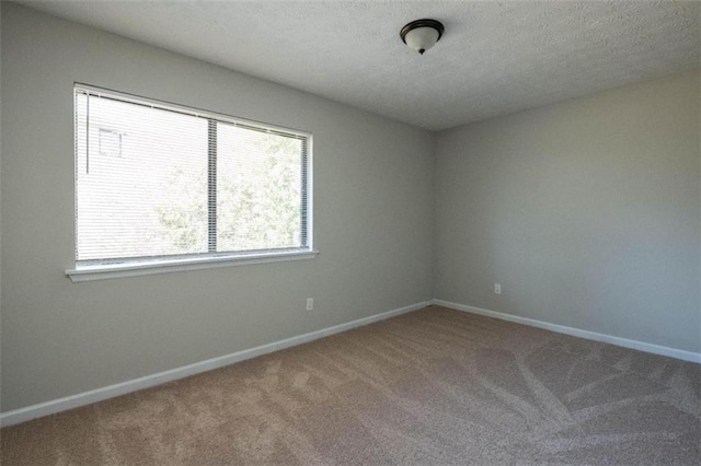 unfurnished room with carpet floors, a textured ceiling, and baseboards