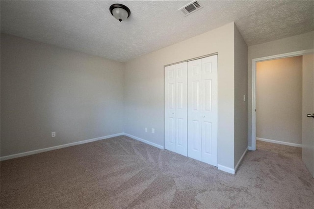 unfurnished bedroom featuring a textured ceiling, visible vents, baseboards, a closet, and carpet