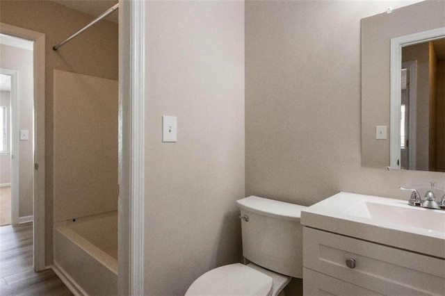 bathroom featuring wood finished floors, shower / tub combination, vanity, and toilet