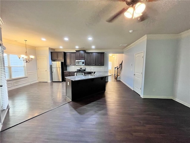 kitchen with dark wood-type flooring, hanging light fixtures, crown molding, an island with sink, and appliances with stainless steel finishes