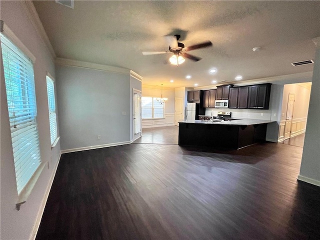 kitchen featuring dark wood-type flooring, stainless steel appliances, decorative light fixtures, ceiling fan with notable chandelier, and ornamental molding