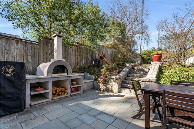 view of patio with exterior kitchen, outdoor dining space, and fence