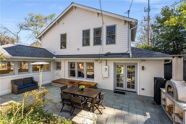 back of property with french doors, brick siding, roof with shingles, and a patio area