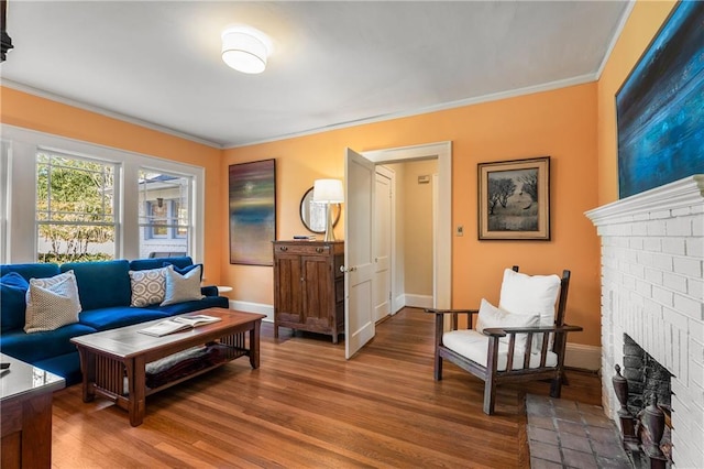 living room with light wood-type flooring, ornamental molding, a fireplace, and baseboards