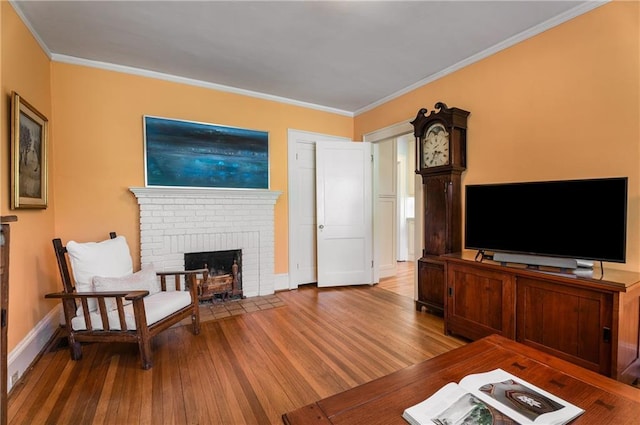 living area featuring a brick fireplace, ornamental molding, and wood finished floors