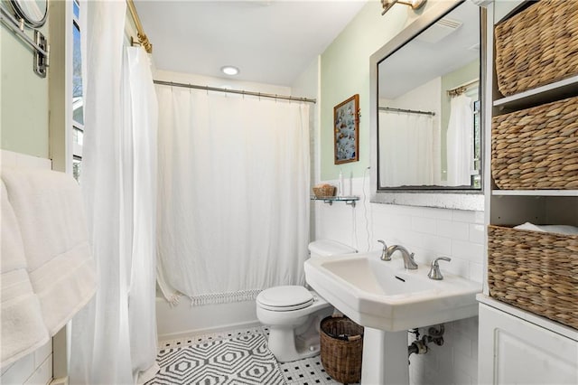 bathroom featuring shower / bath combo with shower curtain, tile walls, toilet, and tile patterned floors